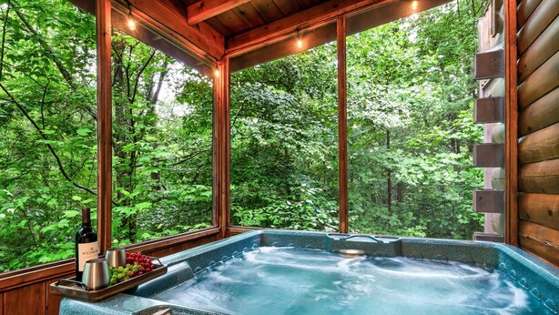 A hot tub with a wooden deck and a wooden cabin in the background.