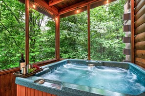 Een hottub met een houten terras en een houten hutje op de achtergrond.