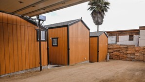Un bâtiment à l’extérieur en bois, doté d’un porche et dont le sol est en terre battue.