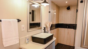 Une salle de bain avec un lavabo blanc, un miroir et une douche.