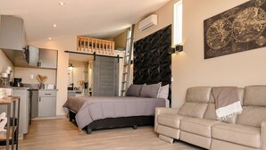 Une chambre moderne comprenant un lit, un canapé, un coin cuisine et un espace en mezzanine.