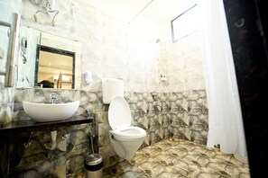Een badkamer met een marmeren wastafel, toilet en douche.