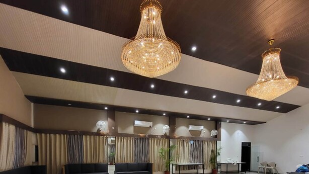 A spacious lobby with two large chandeliers, a seating area with sofas, and a reception desk. - TGI Insignia Resort & Villa's (Bhopal)