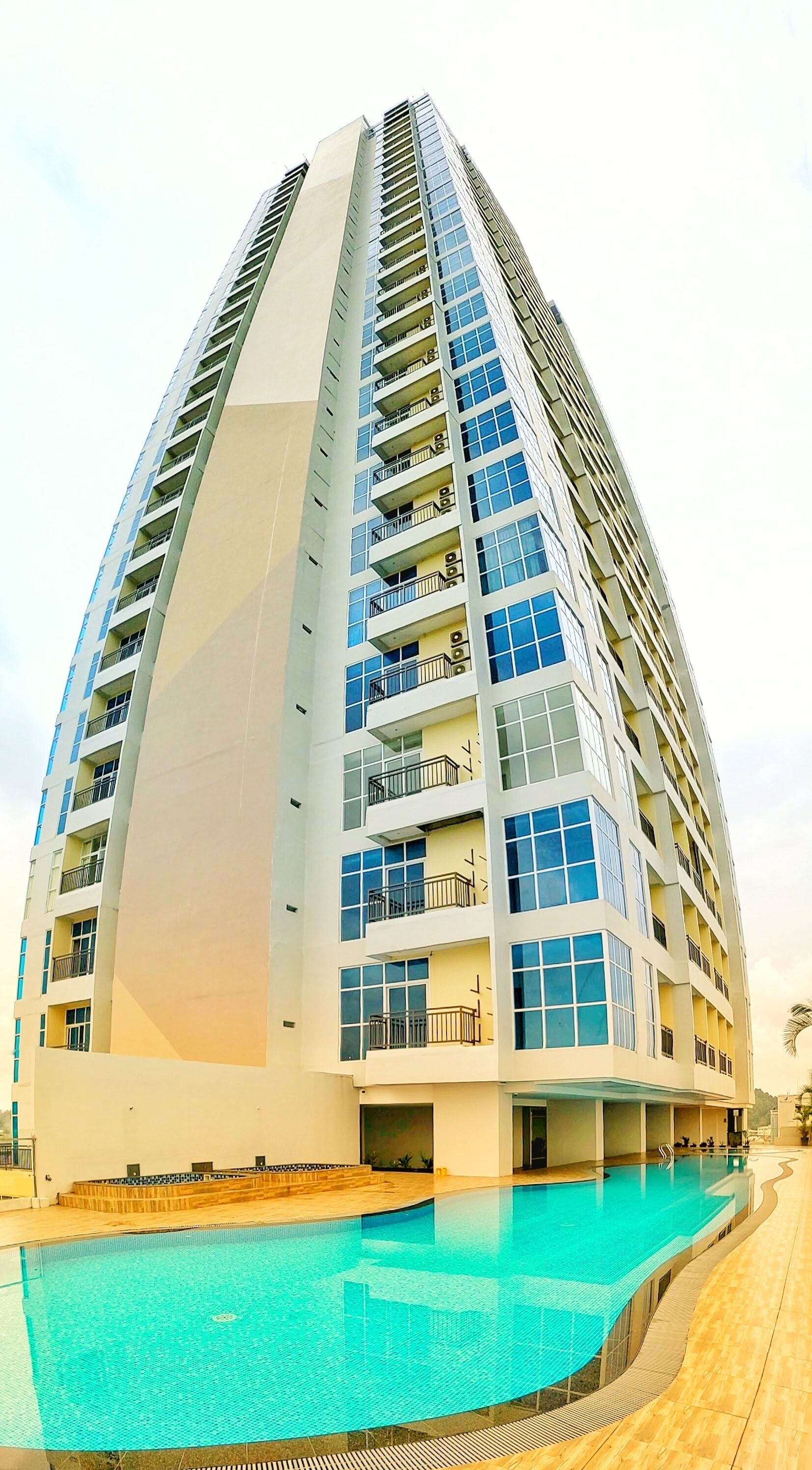 A high-rise hotel with multiple balconies and a swimming pool.