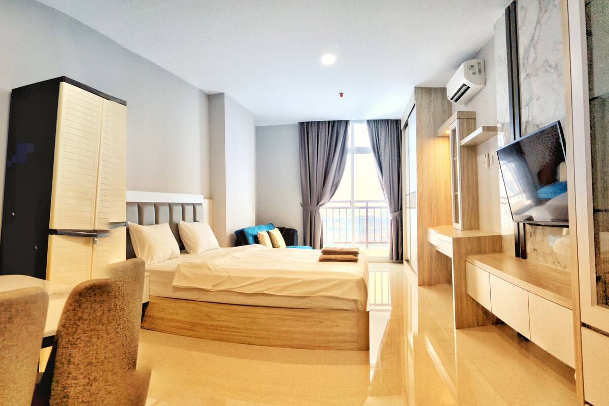 Ein Hotelzimmer mit Bett, Schreibtisch, Fernseher, Kleiderschrank und einem Fenster mit Vorhängen.