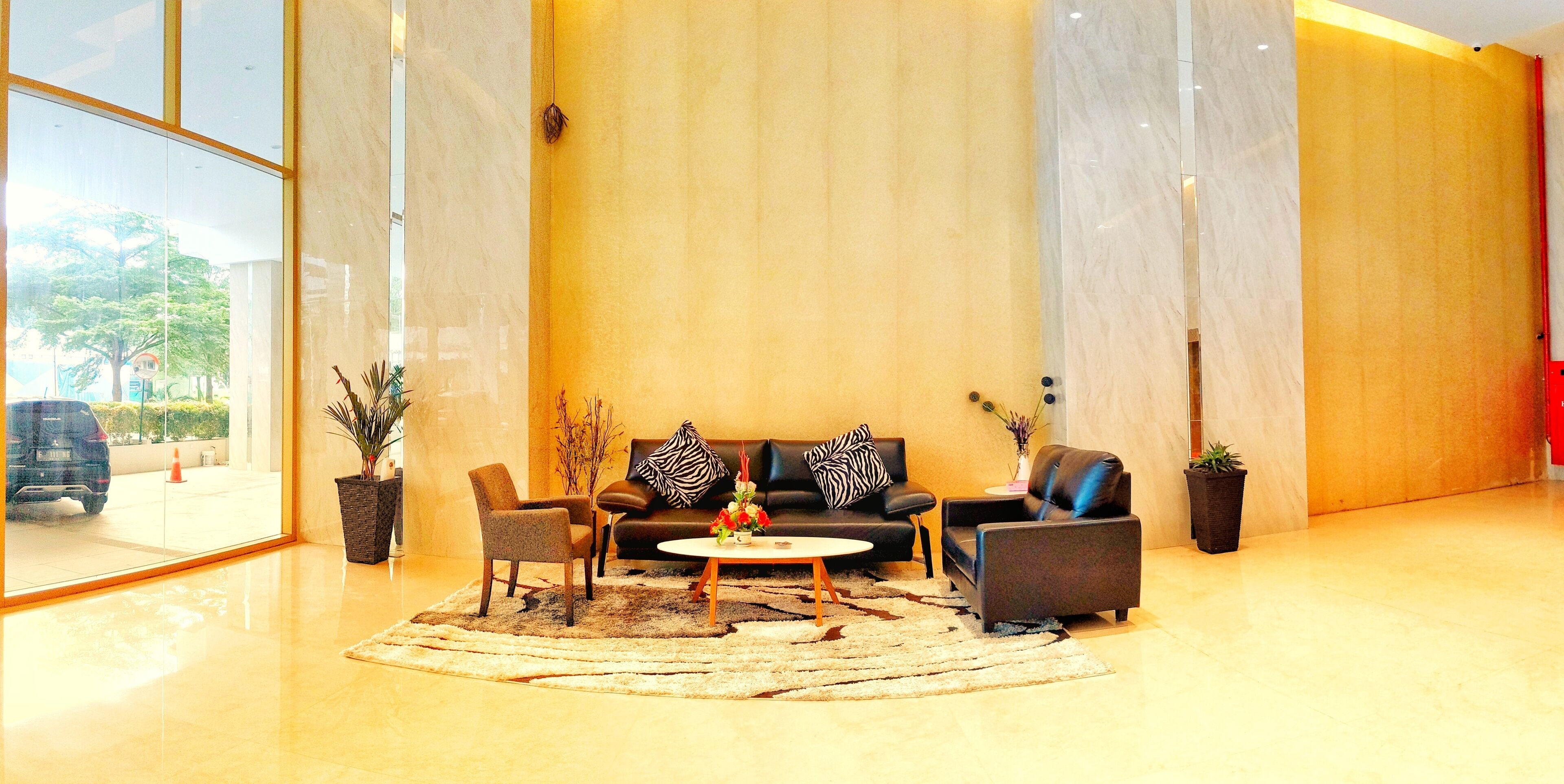 A modern lobby with a sofa set, a coffee table, and a potted plant.