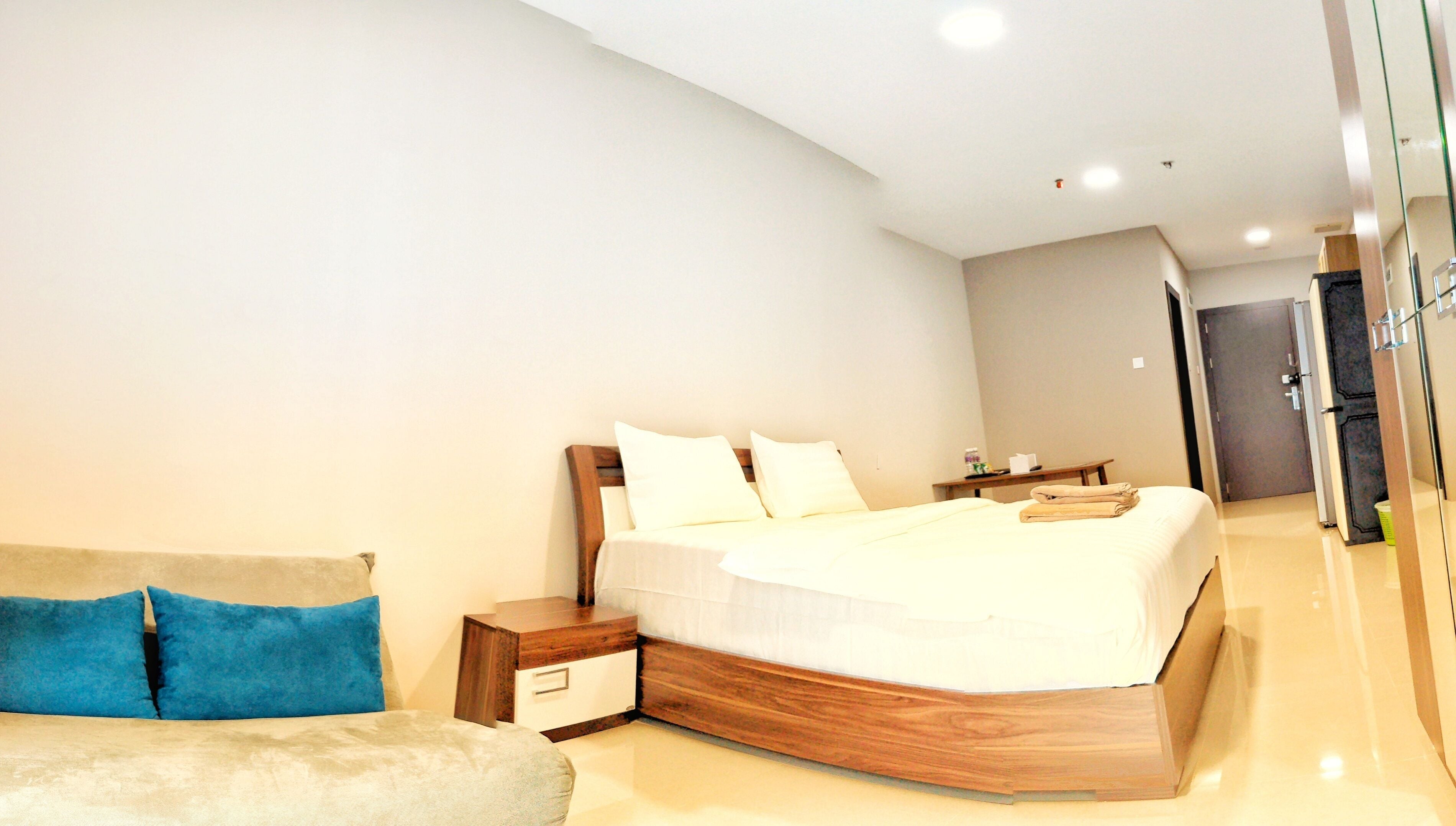 Un dormitorio moderno con una cama grande, mesitas de noche y un sofá.