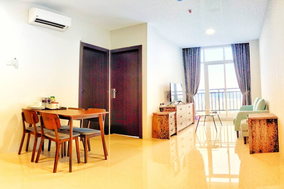 Ein Hotelzimmer mit Essbereich, einer Couch und einem Fenster mit Vorhängen.