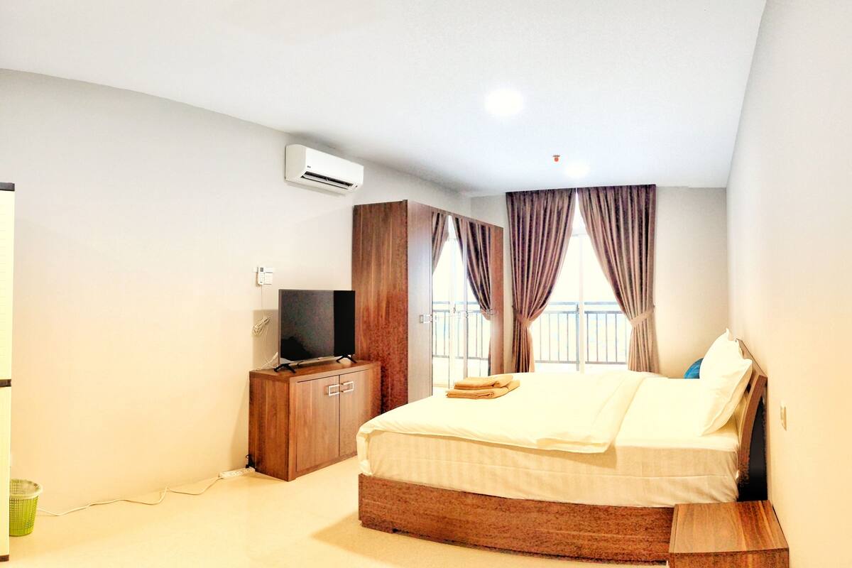 Ein Hotelzimmer mit Bett, Fernseher, Kleiderschrank und Klimaanlage.