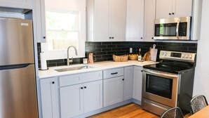 Una cocina moderna con armarios azul claro, un refrigerador de acero inoxidable, un microondas y un horno.