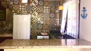 A kitchen with patterned tiles, a white refrigerator, and a granite countertop. - Big Island Longa Beach. (Angra dos Reis)