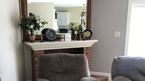 A living room with two grey armchairs, a fireplace mantel with decorative items, and a large mirror above it. - Residential home all hardwood floor, ten minutes from downtown. No pets aloud. (Lexington)