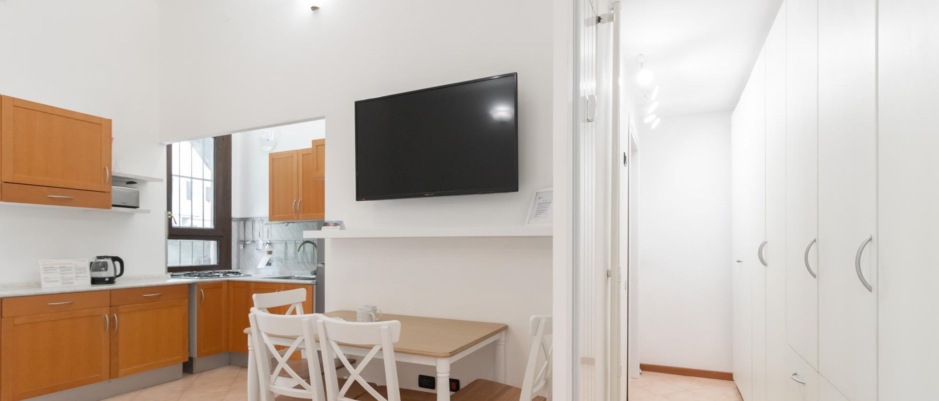 Una cocina moderna con armarios de madera, horno empotrado y televisor de pantalla plana.