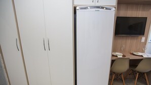 A kitchenette with a white refrigerator, a wooden countertop, two chairs, and a flat-screen TV mounted on the wall. - 5 Minutes From Copacabana Beach Nsc1109 (Rio de Janeiro)