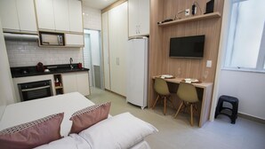 A compact kitchen with a microwave, refrigerator, and a dining area with a TV above. - 5 Minutes From Copacabana Beach Nsc1109 (Rio de Janeiro)