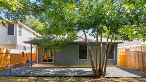 Ein Garten mit einem kleinen Gerätehaus, einem Baum und einem Holzzaun.