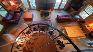 Un intérieur chaleureux avec un escalier en colimaçon, des canapés en cuir et une cheminée en pierre.