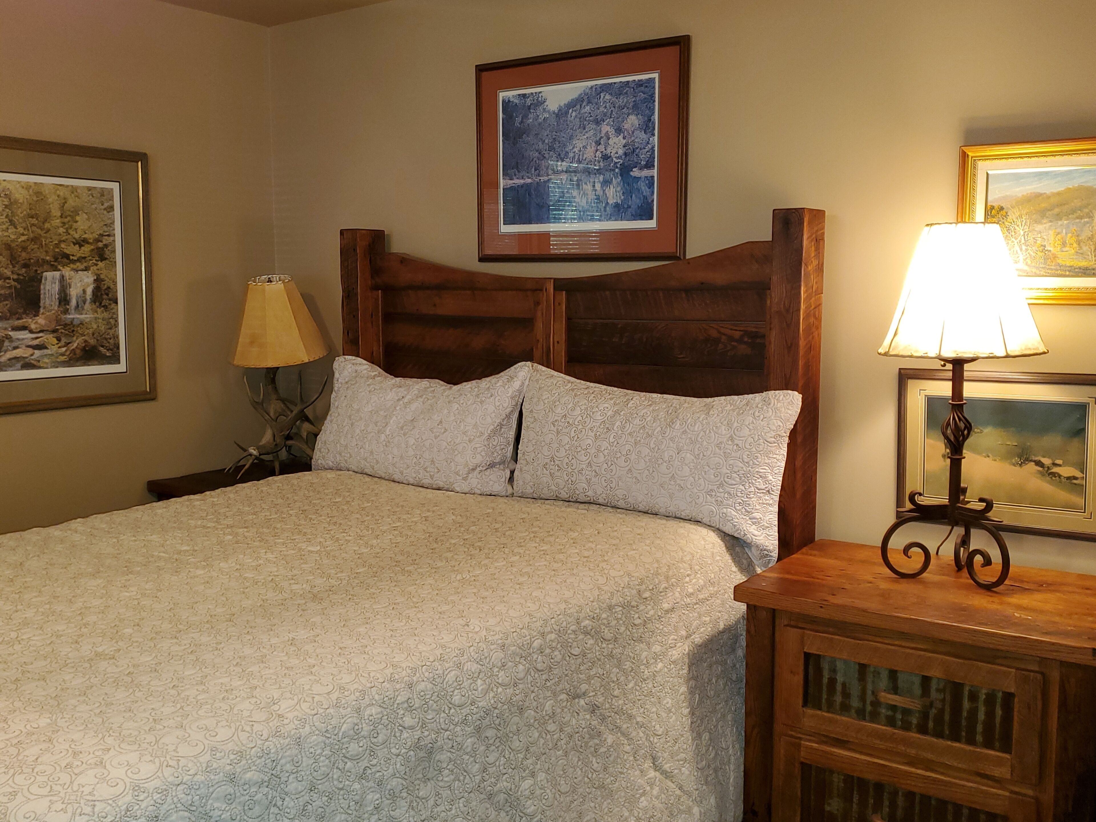 A neatly made bed with patterned bedding, a wooden headboard, and two bedside lamps.