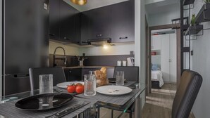 A modern kitchen with dark cabinetry, a dining table set with plates, glasses, and a loaf of bread.