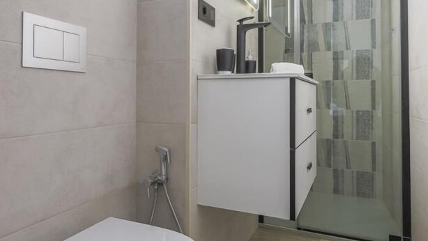 A modern bathroom with a shower, a toilet, and a vanity with a mirror.