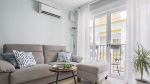 A modern living room with a sofa, a small table with a tray, and a potted plant.