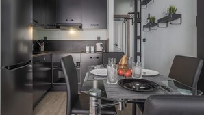A modern kitchen with dark cabinetry, a built-in oven, and a dining area with a table set for two.