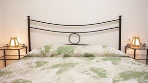 Ein Bett mit Metallgestell, zwei Nachttische mit Lampen und eine Bettdecke mit Blumenmuster.
