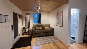 A modern living room with a wooden ceiling, a sofa, a small table, and a window.