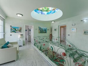 Ein Flur mit Glastrennwand, einem weißen Sofa und einem Gemälde an der Wand.