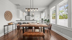 Une cuisine moderne avec des meubles blancs, un îlot central et un luminaire suspendu.