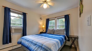 A bedroom with a bed, a ceiling fan, a window with curtains, a bedside lamp, and a small table. - Clean & Cozy 1BR Apt#6 w/Full Kitchen & Private Bath (Ellsworth)