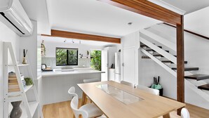 A modern kitchen with white cabinetry, a wooden ceiling, and a staircase with a wooden railing.
