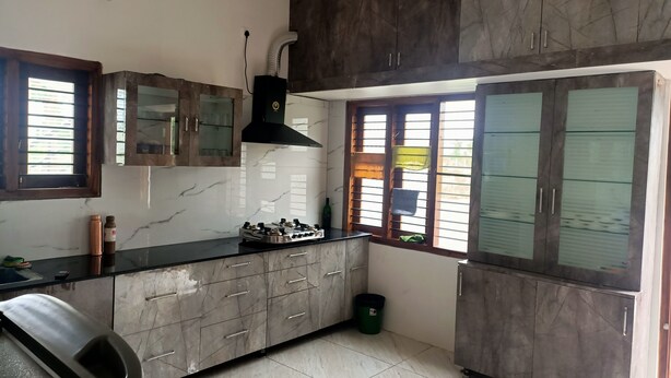 Una cocina con encimeras de mármol, armarios oscuros, una estufa a gas y una ventana con persianas.