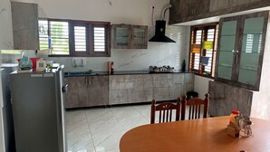 Una cocina con refrigerador, estufa y mesa de comedor con sillas.