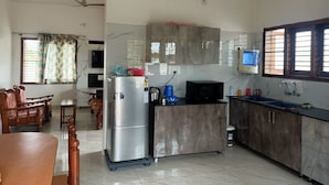 Una cocina equipada con refrigerador, microondas y gabinetes de madera. Hay un comedor con mesa y sillas.