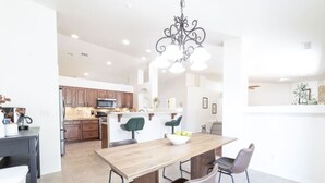 A modern kitchen with wooden cabinets, a central island, and a dining area with a wooden table and chairs. - *Gas Fireplace *Spacious *Family Friendly *Hot Tub (Prescott)