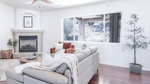 A modern living room with a fireplace, a large window, and a ceiling fan. - *Gas Fireplace *Spacious *Family Friendly *Hot Tub (Prescott)