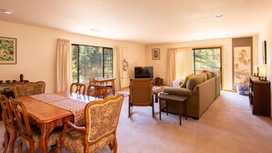 A spacious living room with a dining area, a sofa, and a television. - ☀️🌲Falcons Perch: Nature Lover's Dream, in coastal hills above Blue Lake🪶 (Mckinleyville)
