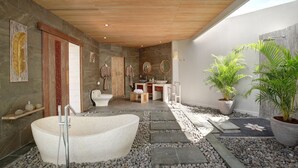 A modern bathroom with a freestanding bathtub, stone walls, wooden ceiling, and potted plants. - Vivara Bali Private Pool Villas & Spa Retreat (Jimbaran)