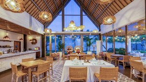 A restaurant with high ceilings, wicker furniture, and large windows overlooking a tropical landscape. - Vivara Bali Private Pool Villas & Spa Retreat (Jimbaran)