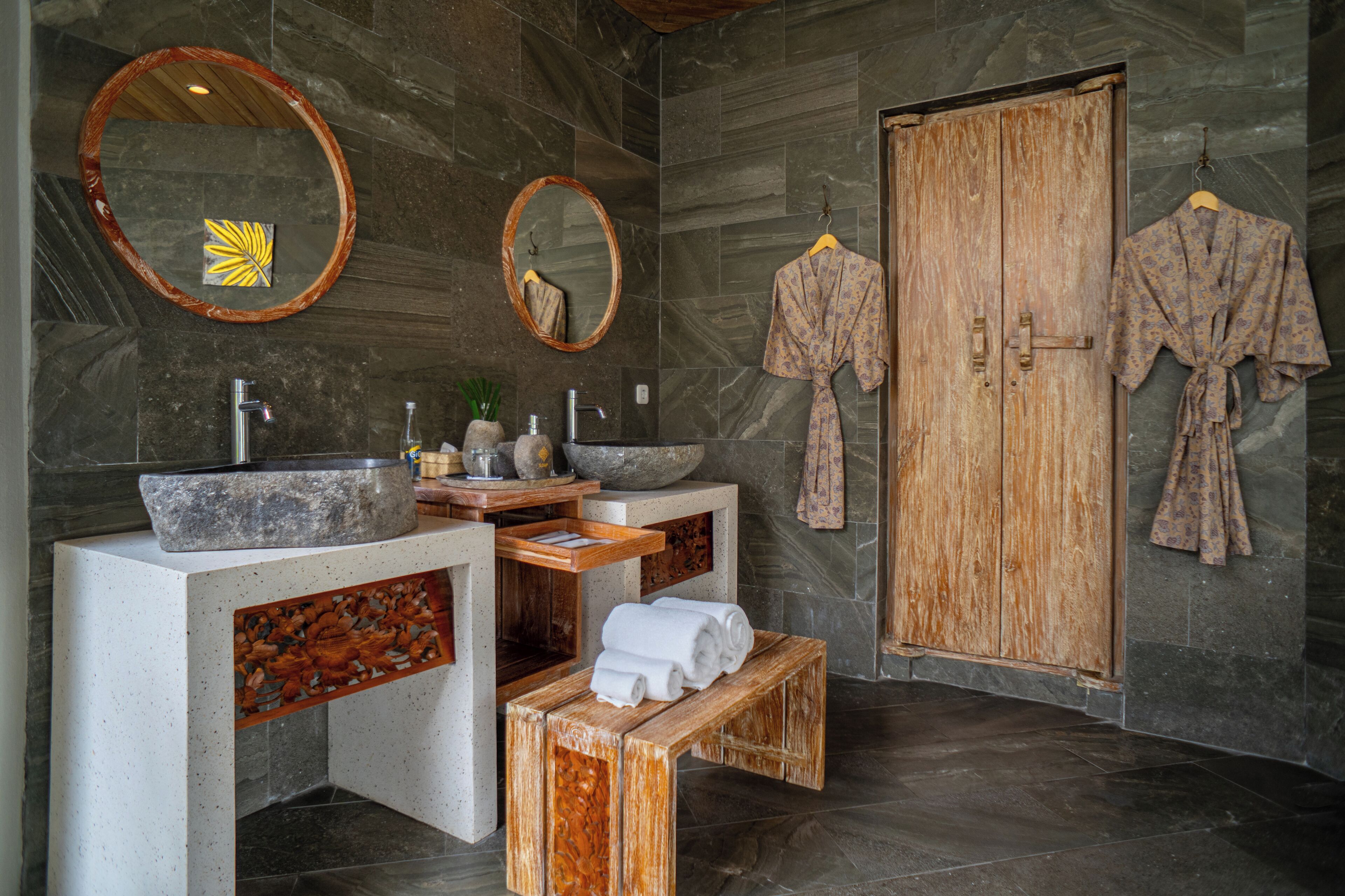 A bathroom with a large mirror, a wooden door, and a robe hanging on the wall.