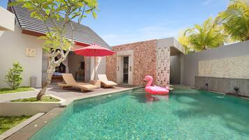 A swimming pool with a pink flamingo float, lounge chairs, and a red umbrella.
