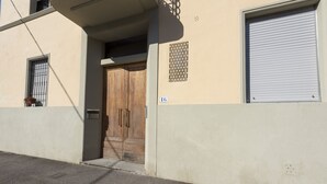 Um edifício com porta de madeira fechada, janela com grades de metal e porta de garagem.