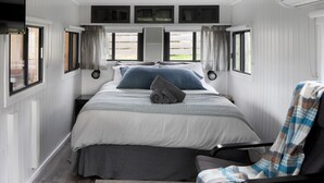 Une chambre à coucher avec un lit, une chaise et une fenêtre avec des rideaux.