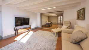 A spacious living room with a flat-screen TV, a sofa, a coffee table, and a dining area with a table and chairs. - Santo Spirito View in Florence by Mmega (Firenze)