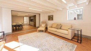 A spacious living area with a sofa, a small table, a chair, and a dining table with chairs. - Santo Spirito View in Florence by Mmega (Firenze)