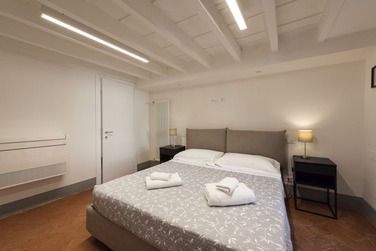 Ein Hotelzimmer mit Bett, Nachttisch, Lampe, Heizkörper und Tür.