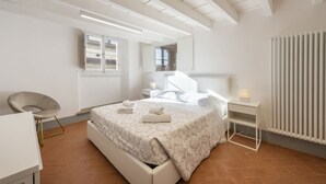 A modern bedroom with a bed, bedside table, chair, and a window. - Santo Spirito View in Florence by Mmega (Firenze)