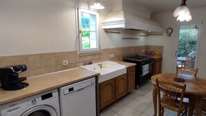 A compact kitchen with a dishwasher, stove, and a dining table with chairs.