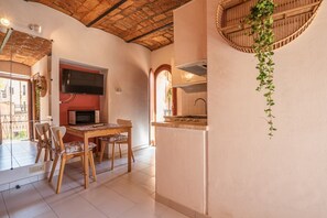 Une cuisine avec une table et des chaises en bois, un four à micro-ondes et une plante suspendue.